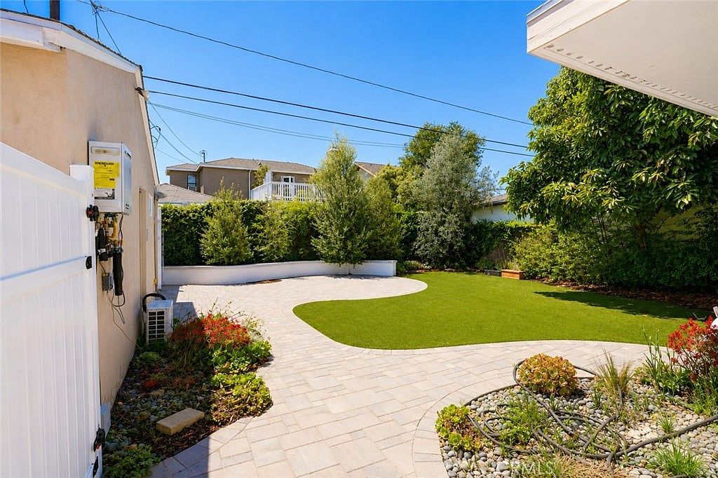 Backyard with pavers, manicured turf, and mature side hedge