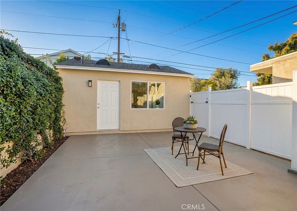 The permitted studio ADU at twilight, a small cream stucco building with its own front door, window, and patio dining set